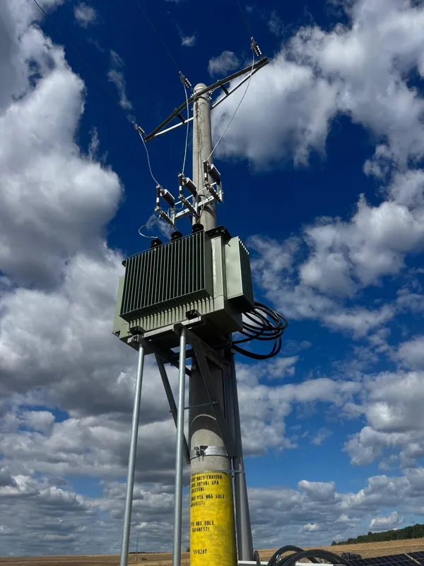 Close-up of the transformer on its pole against a blue sky