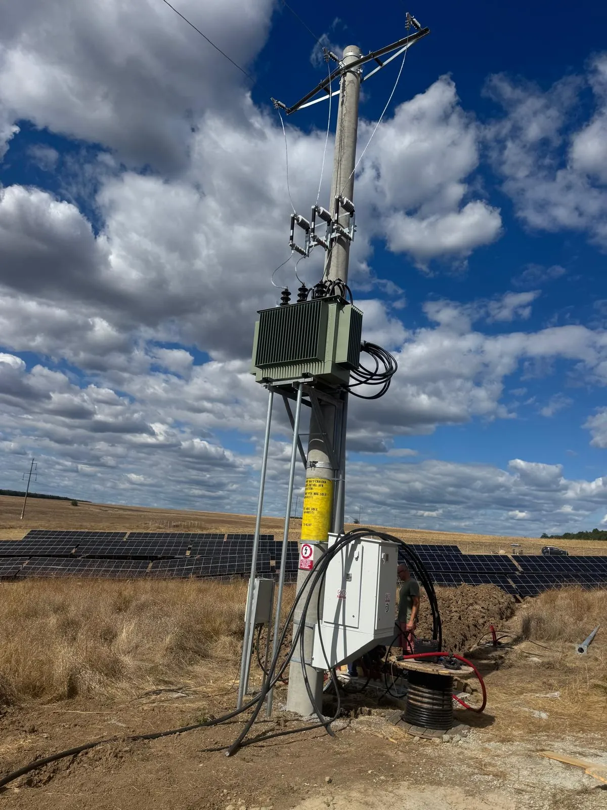 The park's pole-mounted transformer and grid connection, with panel rows behind